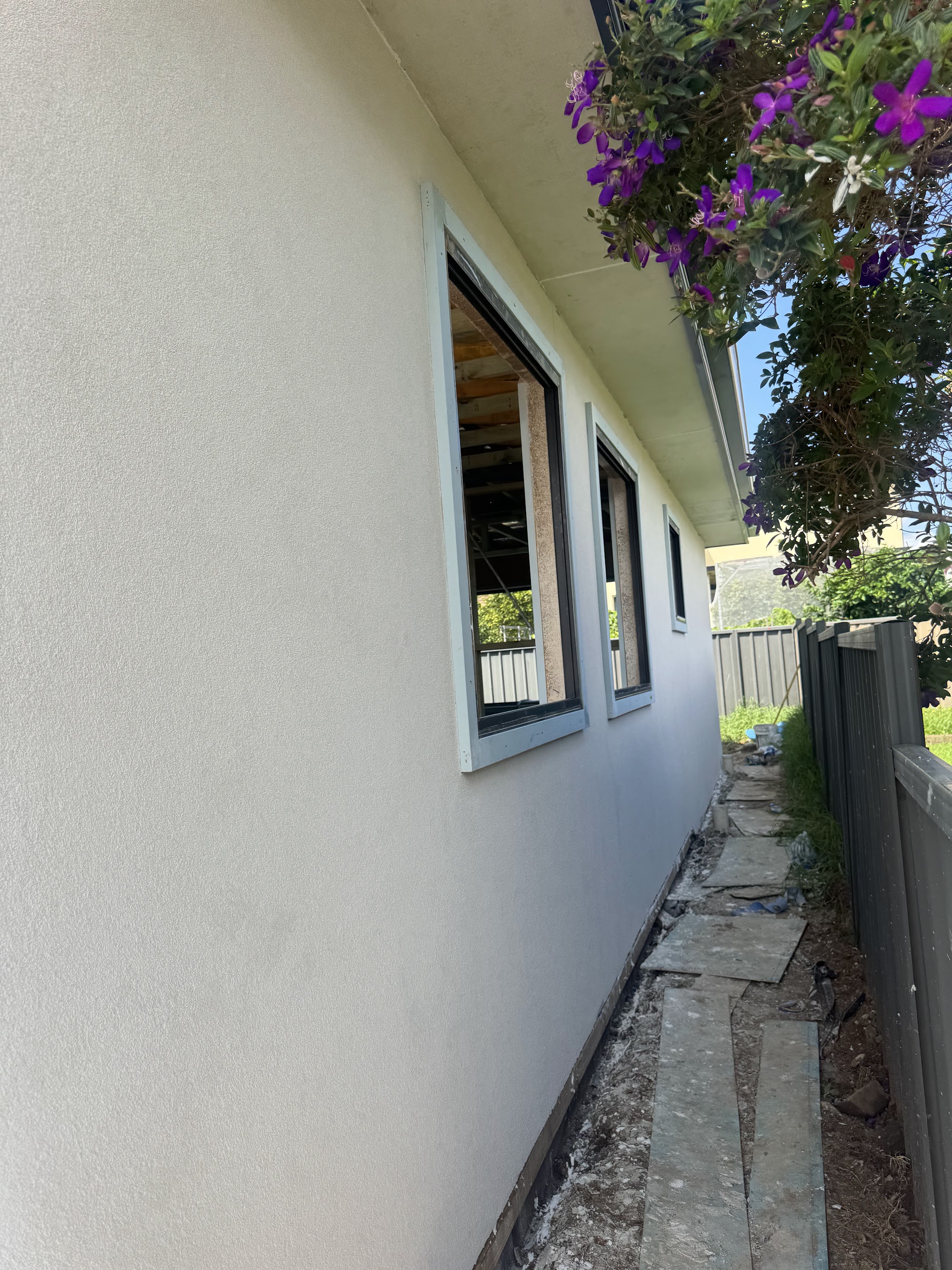 Freshly rendered cream side wall of a house with new window openings