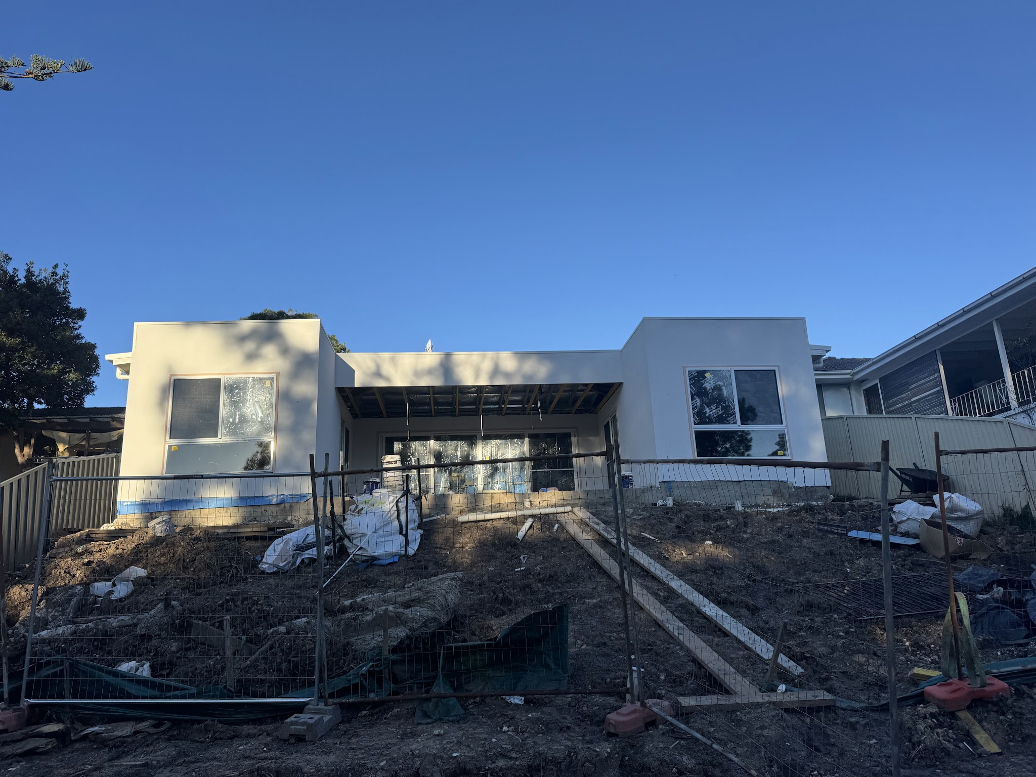 Newly rendered single-storey home with site fencing in front