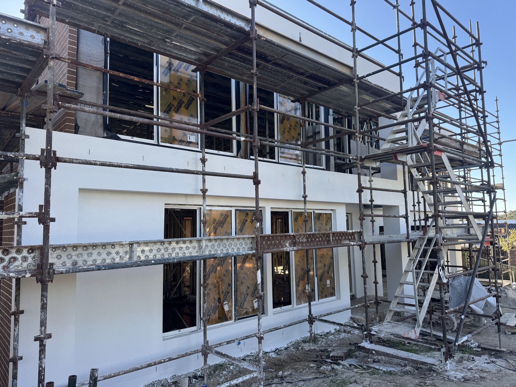 Fresh white render on a two-storey new build with scaffolding up